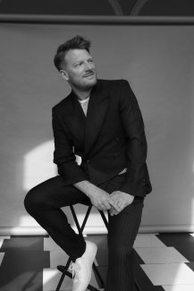 Daniel Schmutzhard in suit on chair